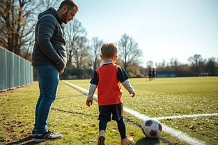 Parent and child at the side of a grassroots football pitch, child going on to play.jpg
