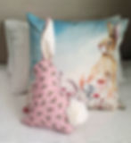 Pink floral bunny toy beside rabbit cushion