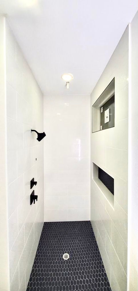 Shower upgrade with white tile and dark tile floor