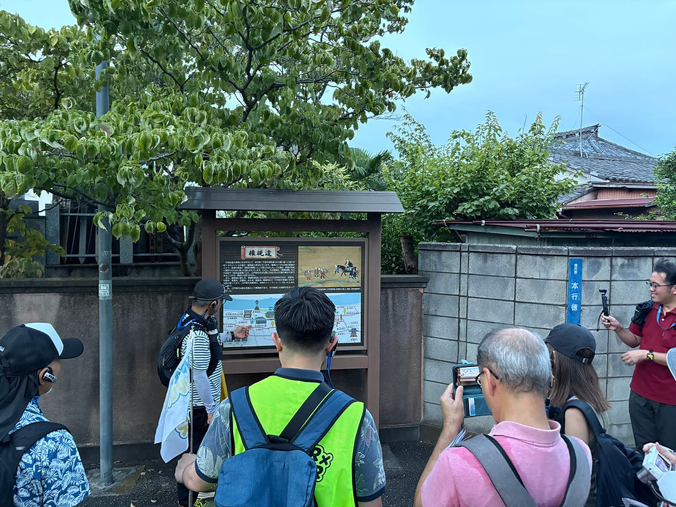 権現道の案内板の前で、古道について説明を聞くツアーの様子