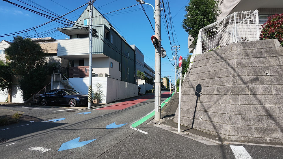 高い擁壁と住宅に挟まれた、上り坂のある道路の分岐