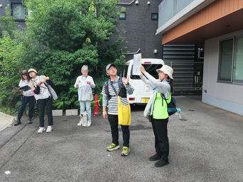 住宅地で地図を使い、京成白鬚線の跡について説明を聞く場面。