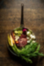 Kosher Beef and Vegetables in a pan on a wooden table at Malka Tel Aviv by Eyal Shani