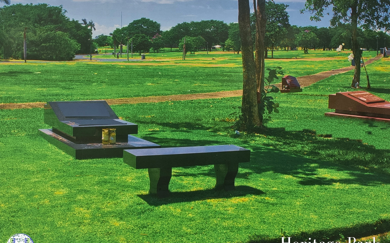 Heritage Park with green grass and black benches, and trees. The Heritage Park.