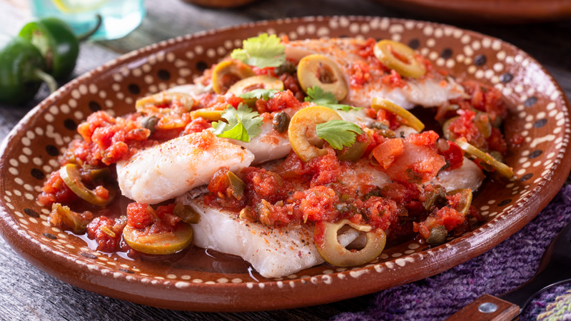 Mexican cooking class in Huatulco – fresh fish on skillet over open fire, authentic seafood recipe preparation.