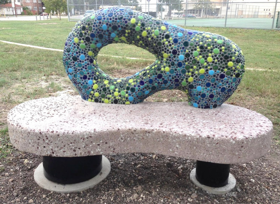 Bench along River Walk in San Antonio Texas that has a Mosaic tiled sculpture as the bench back.