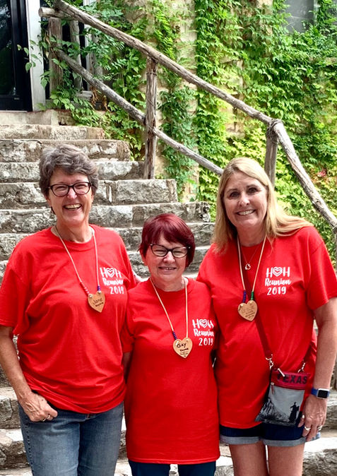 Three women wearing red tee shirts and posing together for the camera