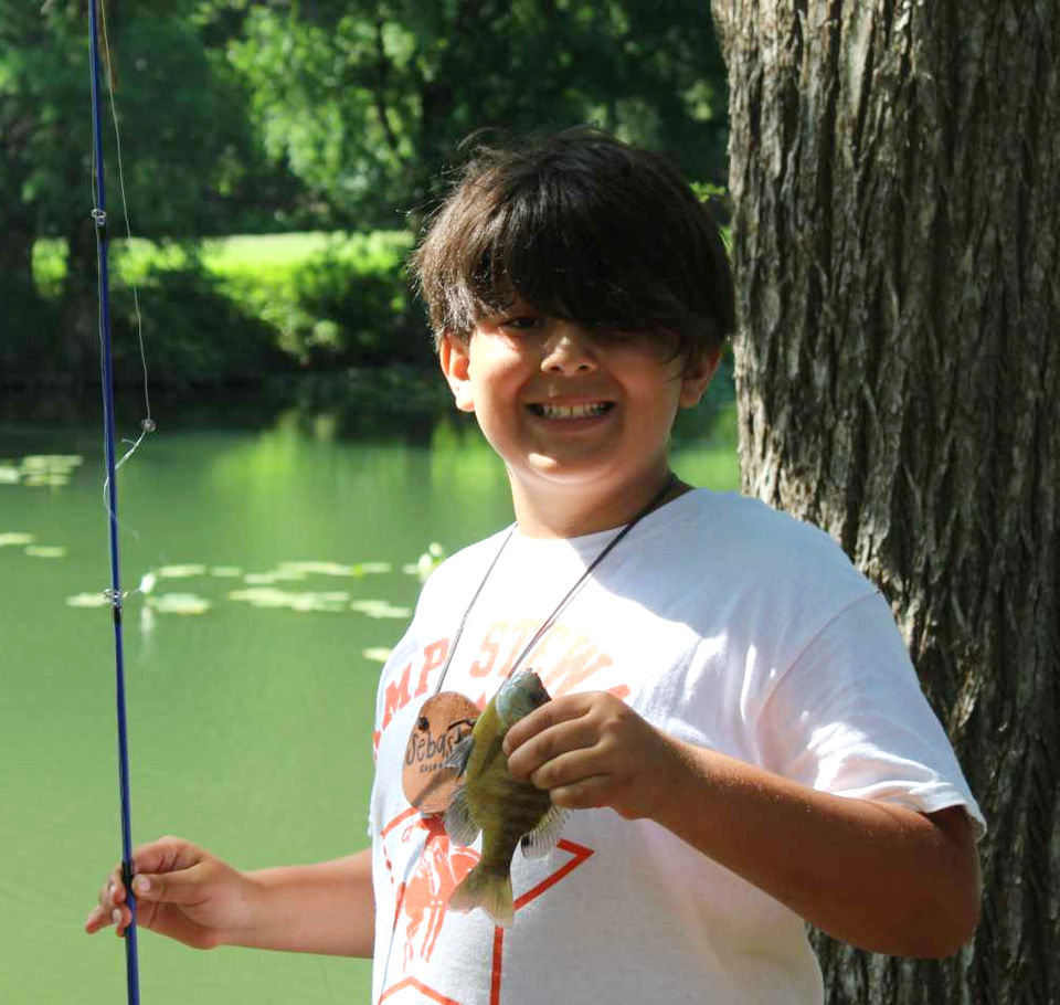 Boy standing outdoors holding a fish