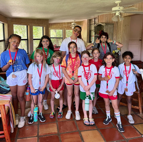 Seven young girls wearing Heart O' the Hills t-shirts and lanyards with 4 older girl counselors or counselors in training.
