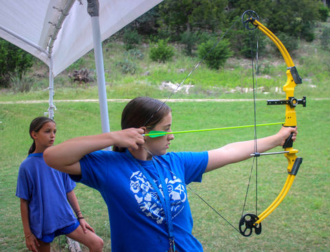 Girl aiming a bow and arrows at a target.