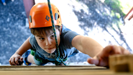 Boy climbing a wall at Camp Stewart; photo taken from above.