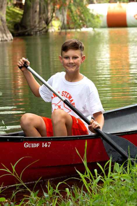 Boy sitting in a canoe on the river, holding an oar