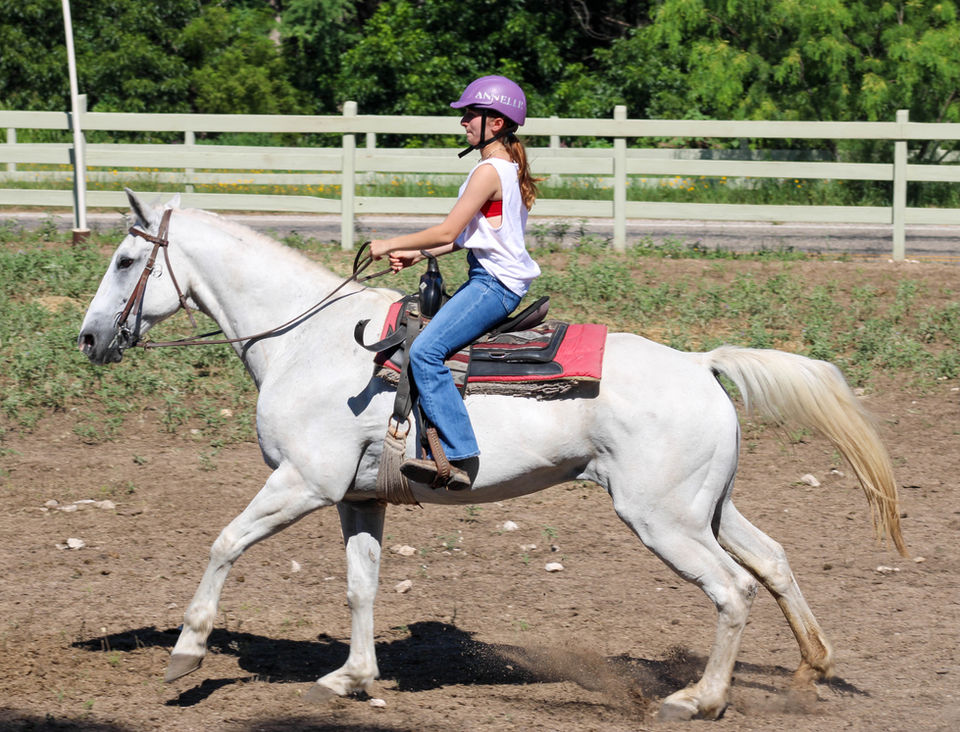 Girl riding a white horse that is running.