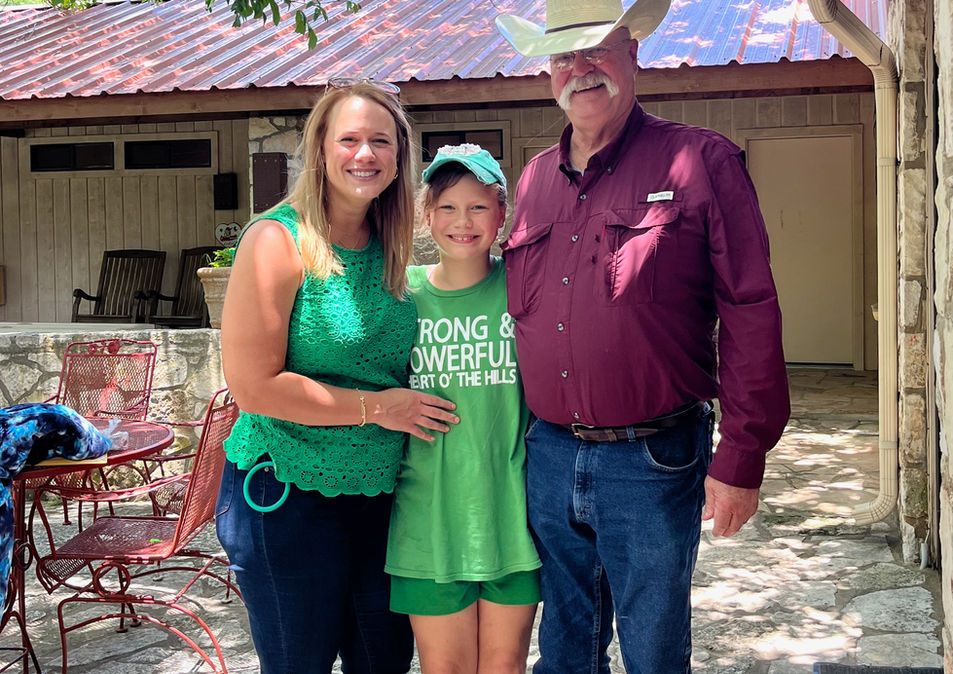 A mother and father with their daughter standing outdoors.