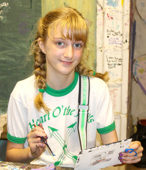 Girl sitting at an arts and crafts table working on a drawing.