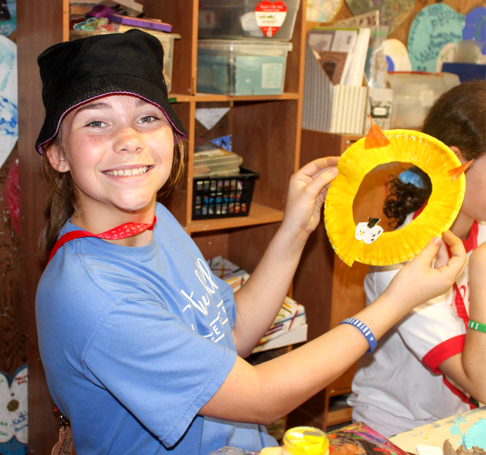 Girl holding up a piece that she made in an arts and crafts class.