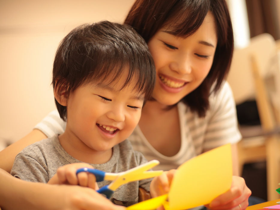 ハサミを使って工作を楽しむ子供と笑顔で見守る母親