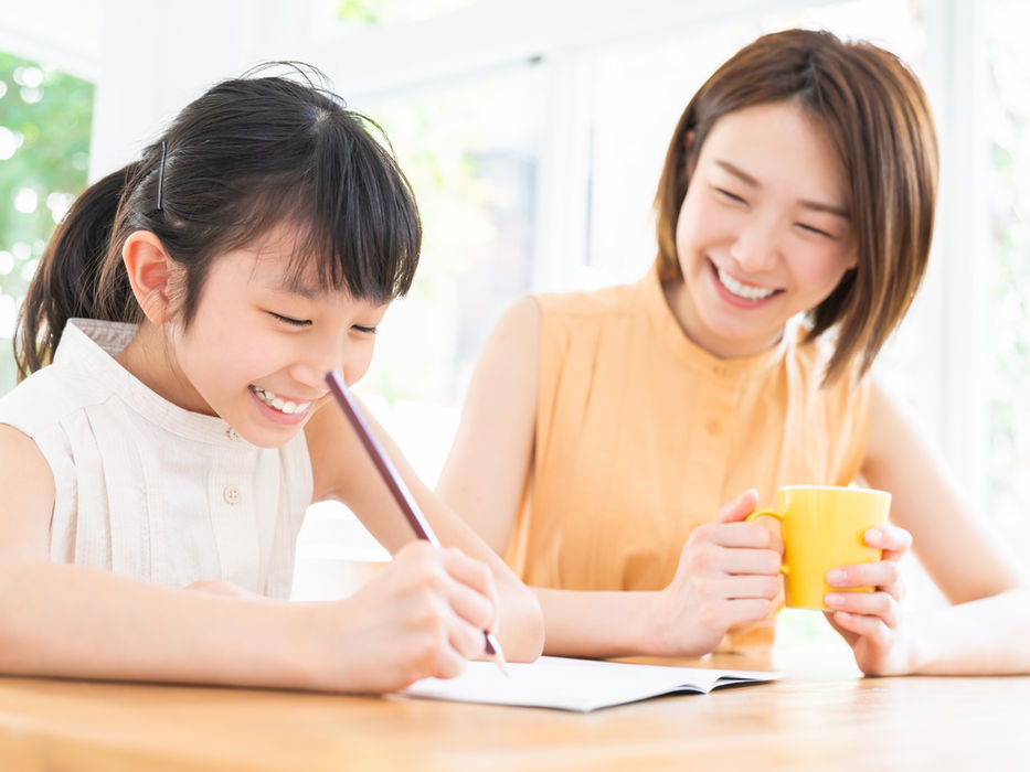 笑顔で勉強する子供を優しく見守る母親