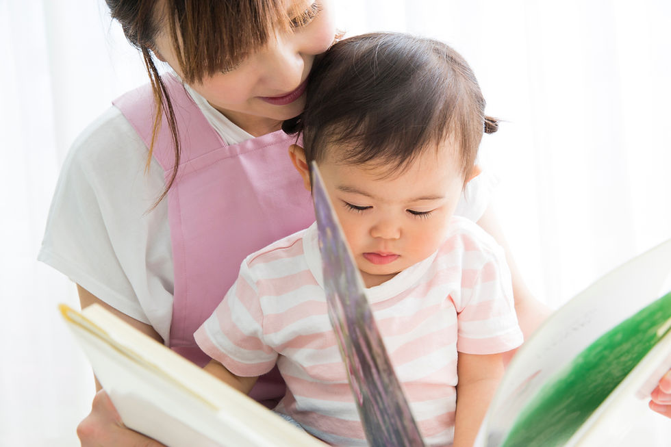 保育士の膝の上で絵本を真剣に見つめる子供