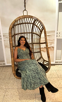 Woman sitting in a hanging wicker chair wearing a green dress