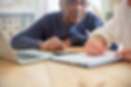 Man watching someone write on pad