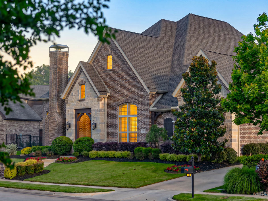 DallasPro architectural exterior photography of a luxury brick home at dawn, showcasing advanced exposure blending that perfectly balances warm interior lighting with a cool morning sky.
