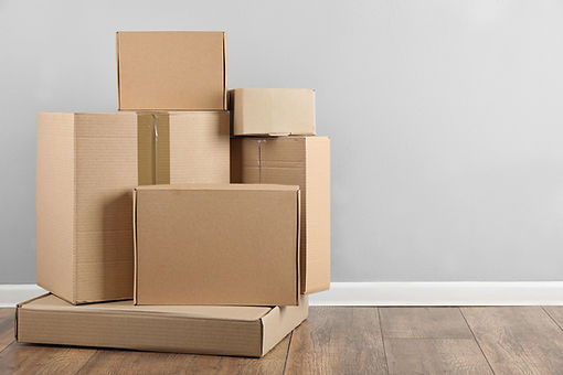 Pile of cardboard boxes near light blue wall indoors. Space for text.jpg