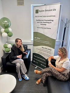 Kirstie and Niki sitting near a banner reading Space Between Us, Confidential Counselling in Grimsby.