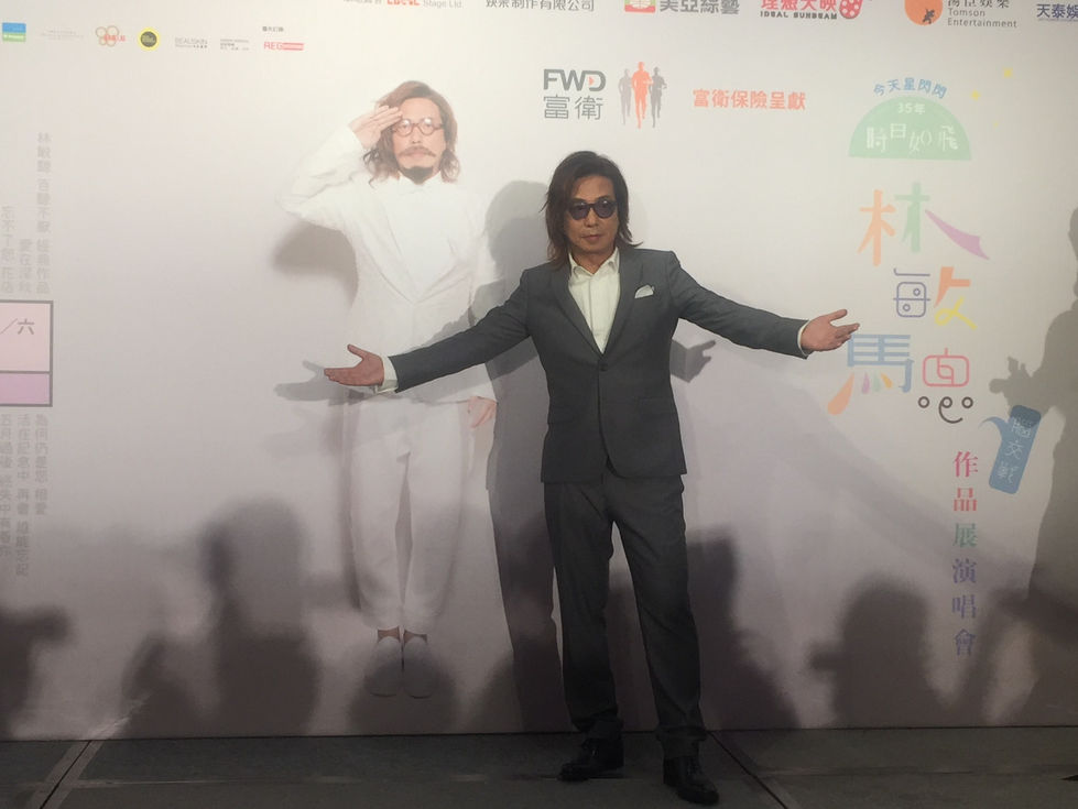 林敏驄身穿灰色西裝,於作品展演唱會記者會現場拍照。