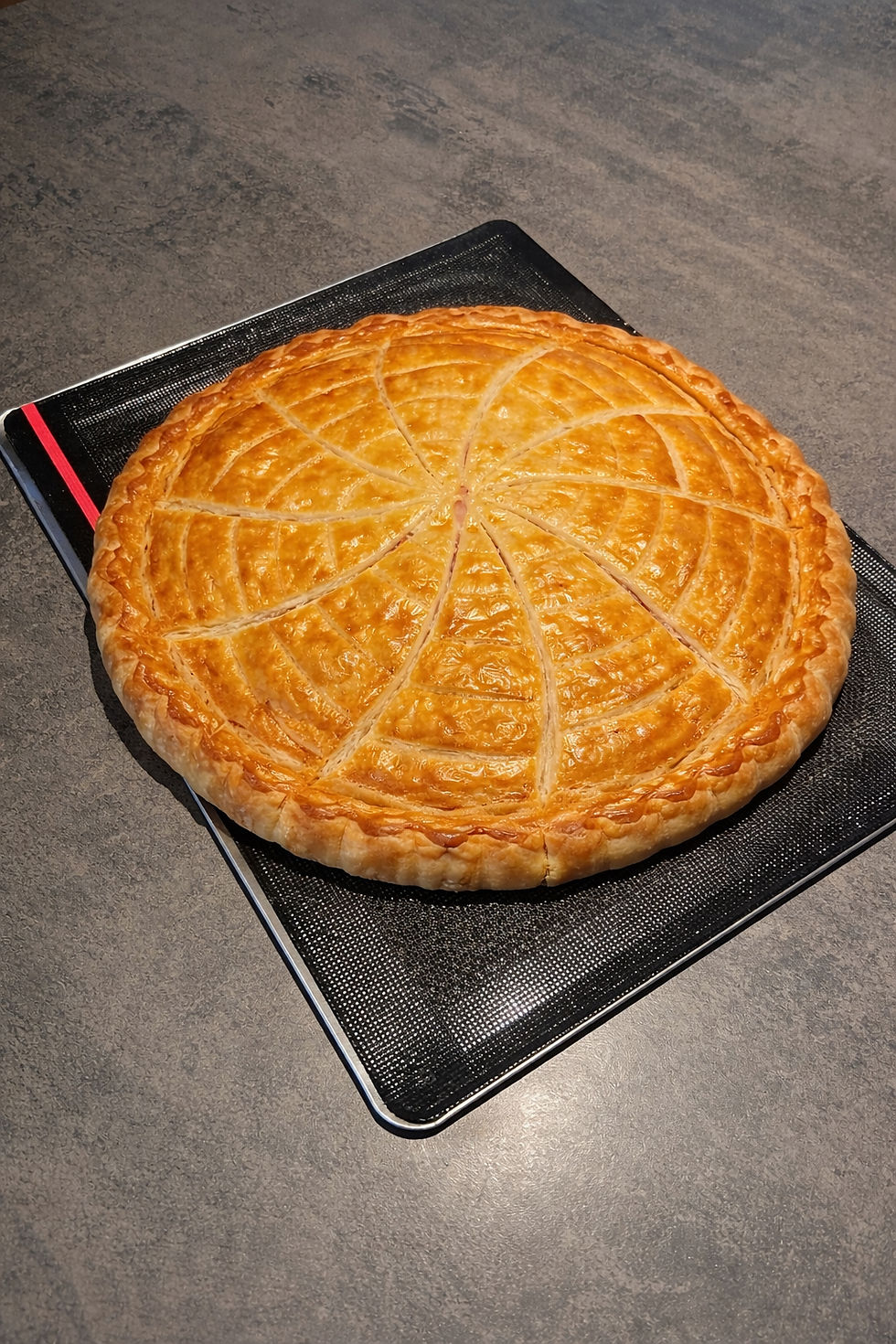 Tourte au jambon et aux champignons maison, entière, dorée et croustillante sur toile boulangère OHRA de Guy Demarle