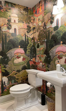 Lush greens and shades of pink highlight a fantasy landscape scenery wallpaper print in a powder room with white fixtures.