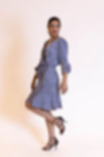 Modelo vestindo um vestido azul com estampa geométrica, mangas três quartos e cintura marcada por um cinto ajustável. Look mo