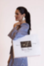 Modelo com vestido estampado azul segurando sacola da Mônica Tyles.