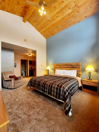 A large guestroom with a King bed and vaulted ceilings in Black River Lodge at North Ironwood Acres near Hurley, Wisconsin