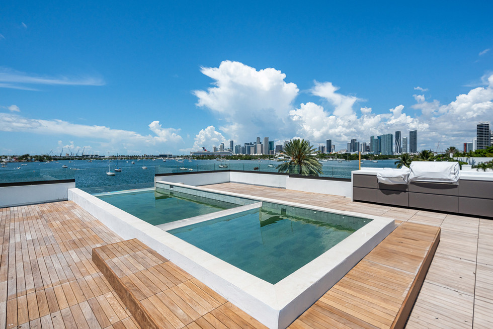 Pool deck with lounge seating, skyline views, and water outlook in a Miami Beach residence