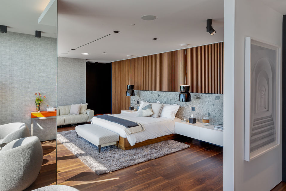 Master bedroom with wood flooring, large bed, seating area, and floor-to-ceiling windows in a Miami penthouse