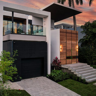 Modern house entrance with steps, landscaping, and wood pivot door in Miami