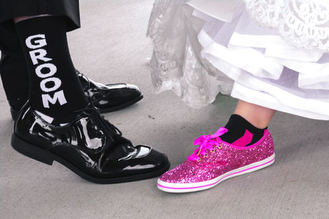Sparkly pink tennis shoes for the bride, and groom wearing black patent leather shoes with "groom" socks