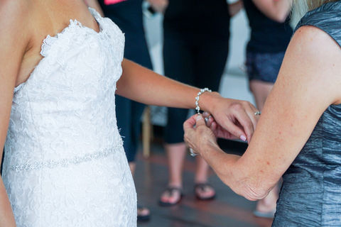 Bridal attendant placing bracelet on bride