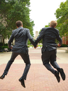 Groom and Best man jumping into the air, perspective from behind