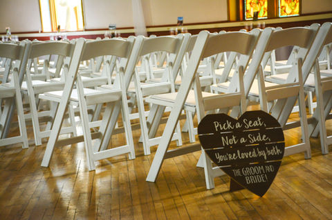 Wedding ceremony chairs set up, with a wooden heart shaped sign informing guests to sit anywhere