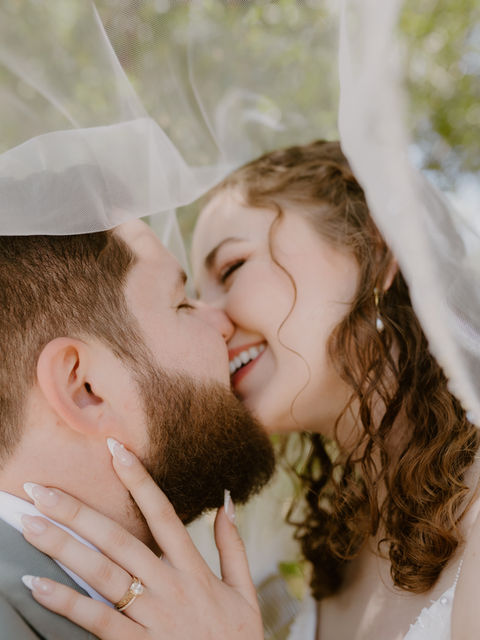 Couple kissing under veil, while smiling