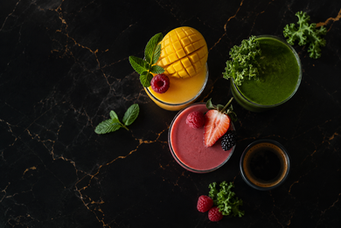 Colourful fruit smoothies made with mango, berries, citrus and fresh green ingredients