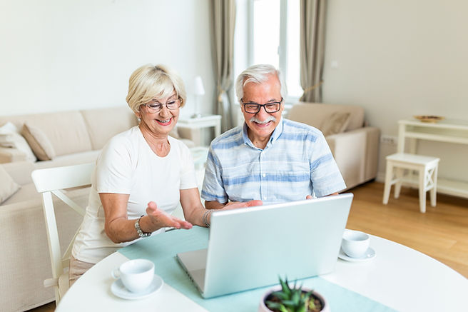 old woman and old man smiling while facing the laptop