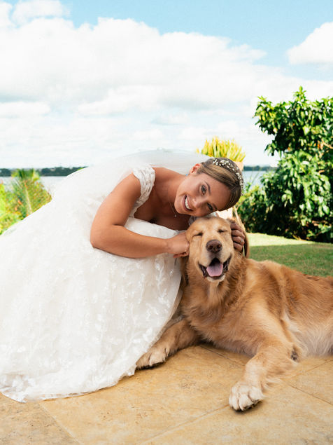 Mariée allongée avec son chien avant la cérémonie dans un jardin tropical.