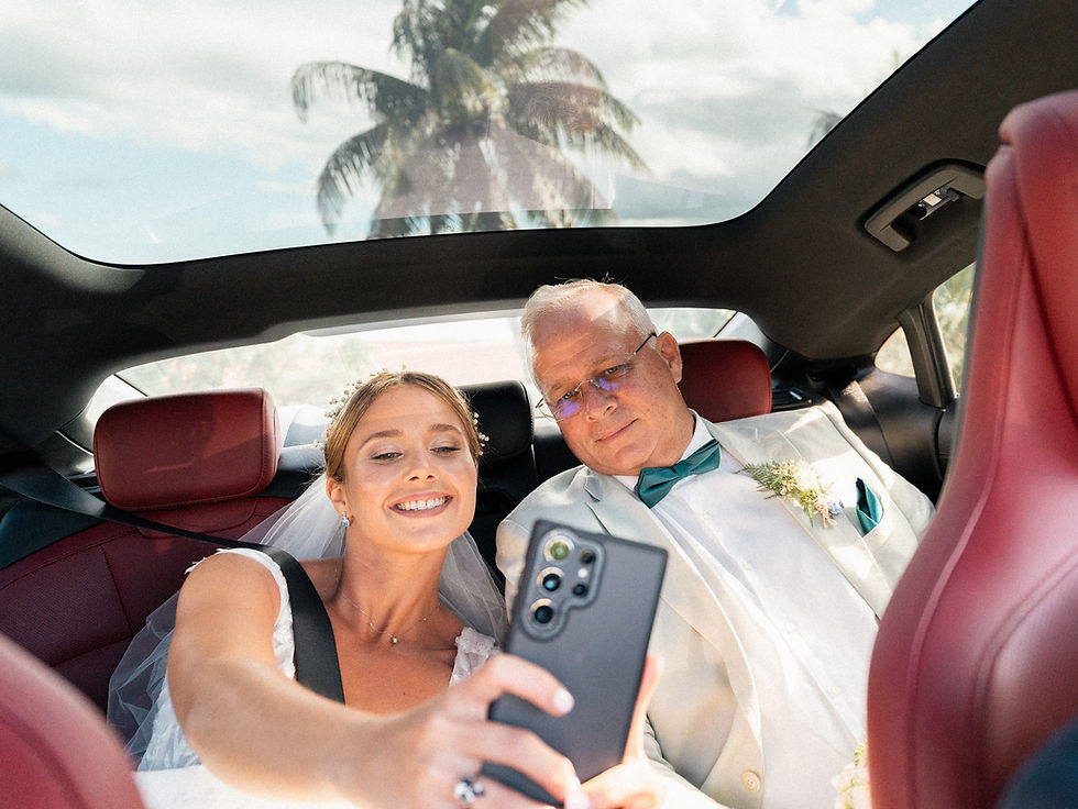 Mariée prenant un selfie avec son père à l’arrière d’une voiture avant la cérémonie, dans une ambiance lumineuse et tropicale en Guadeloupe.