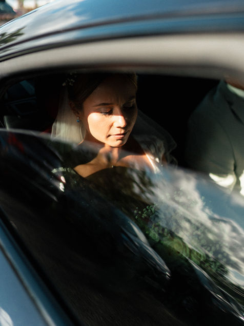 Mariée dans une voiture avant la cérémonie, capturée à travers la vitre avec les reflets du ciel et des palmiers en Guadeloupe.