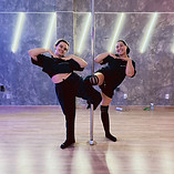 duas mulheres alunas fazendo pose usando a barra de pole dance