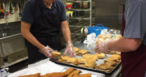 Two people organizing and assembling chicken sandwiches to be served to soup kitchen guests.