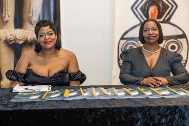 Two woman sitting at the registration table distributing the gala program booklet.